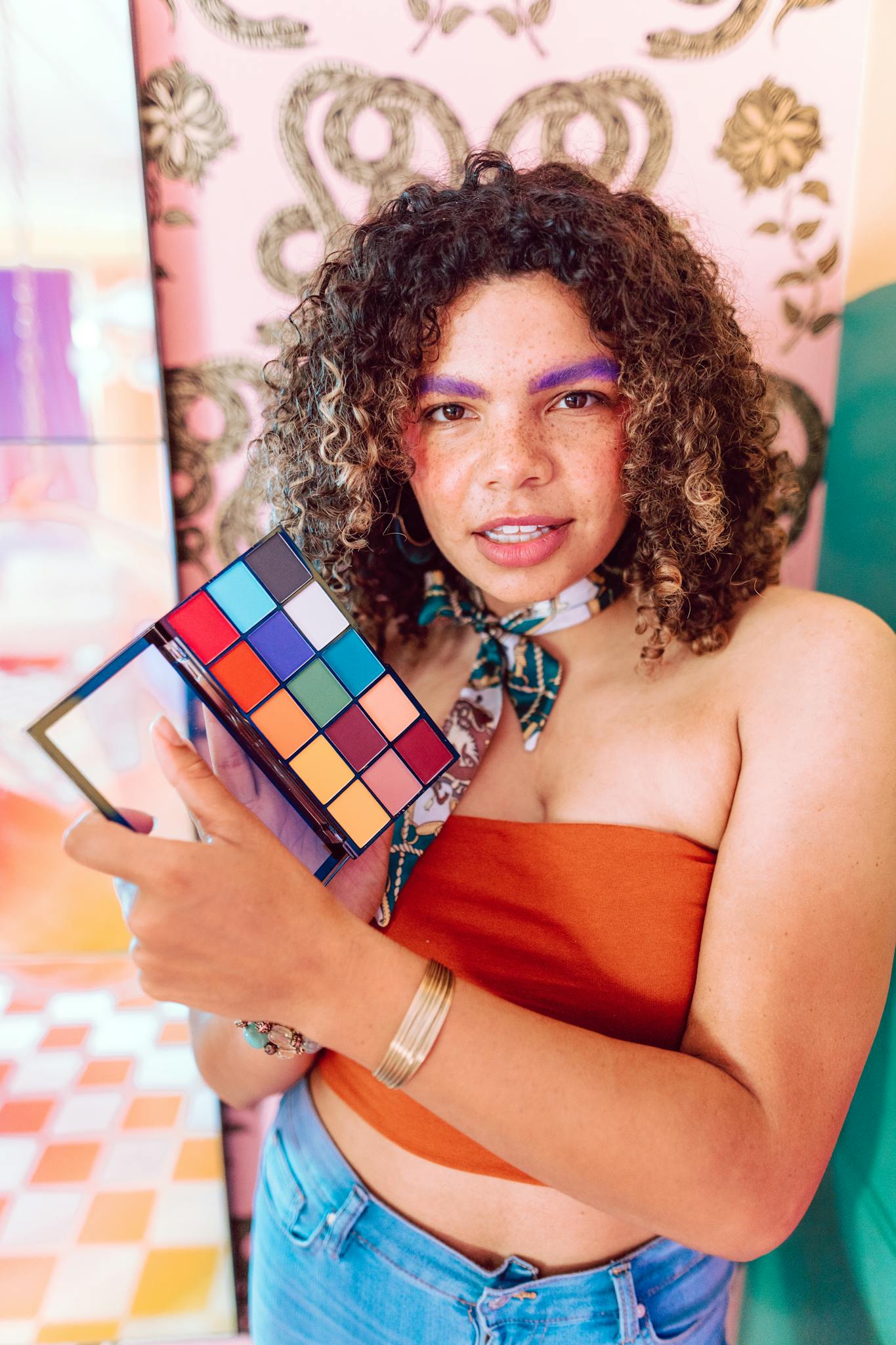 Bright portrait of a woman showcasing colorful makeup in a stylish setting.